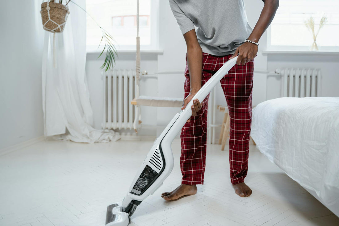 A person cleaning a bedroom with a modern vacuum cleaner, showcasing casual home lifestyle.